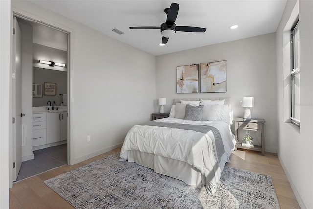 bedroom featuring light wood-type flooring, visible vents, a sink, and baseboards