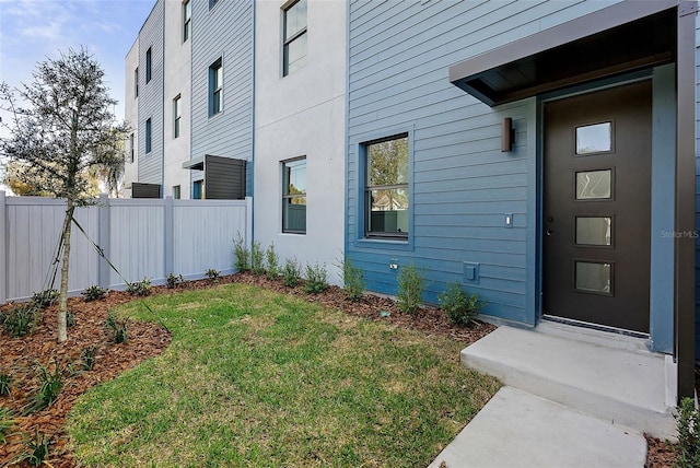 entrance to property featuring a yard and fence