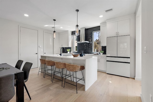 kitchen featuring white cabinets, wall chimney exhaust hood, light countertops, and white refrigerator