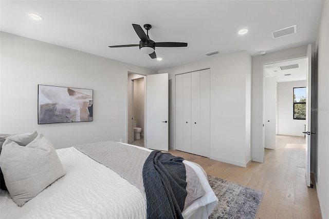 bedroom with light wood finished floors, baseboards, visible vents, and a closet