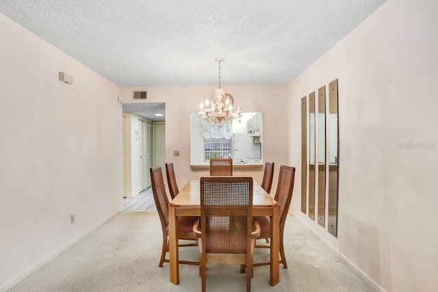 dining room featuring visible vents, light carpet, a textured ceiling, a chandelier, and baseboards