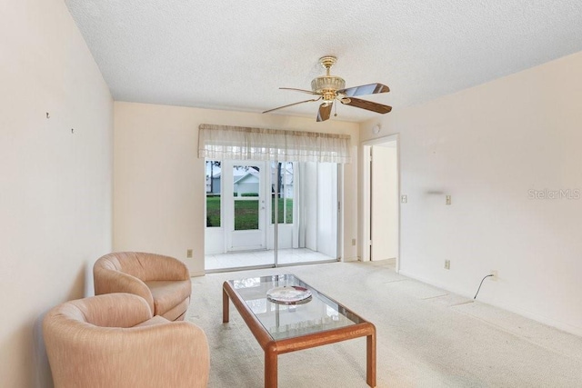 living room with a textured ceiling, a ceiling fan, and light colored carpet