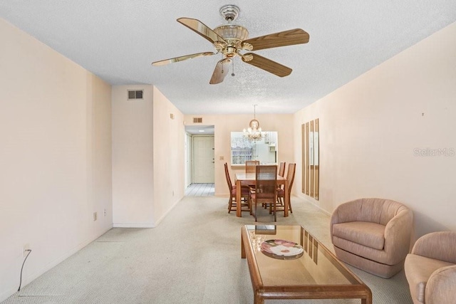 living area featuring light carpet, a textured ceiling, ceiling fan with notable chandelier, and visible vents