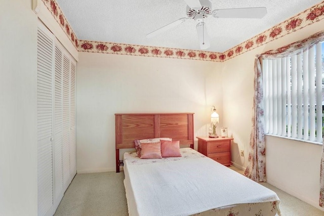 bedroom featuring a ceiling fan, a closet, light carpet, and a textured ceiling