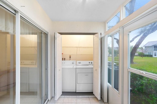 clothes washing area with laundry area, light tile patterned flooring, and washing machine and dryer