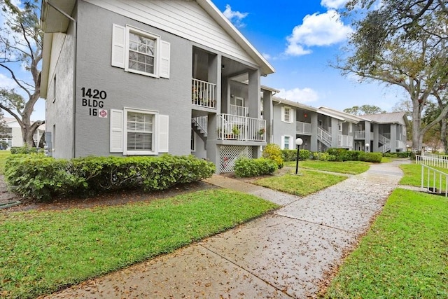 view of front of home with stairs, a front yard, a residential view, and stucco siding