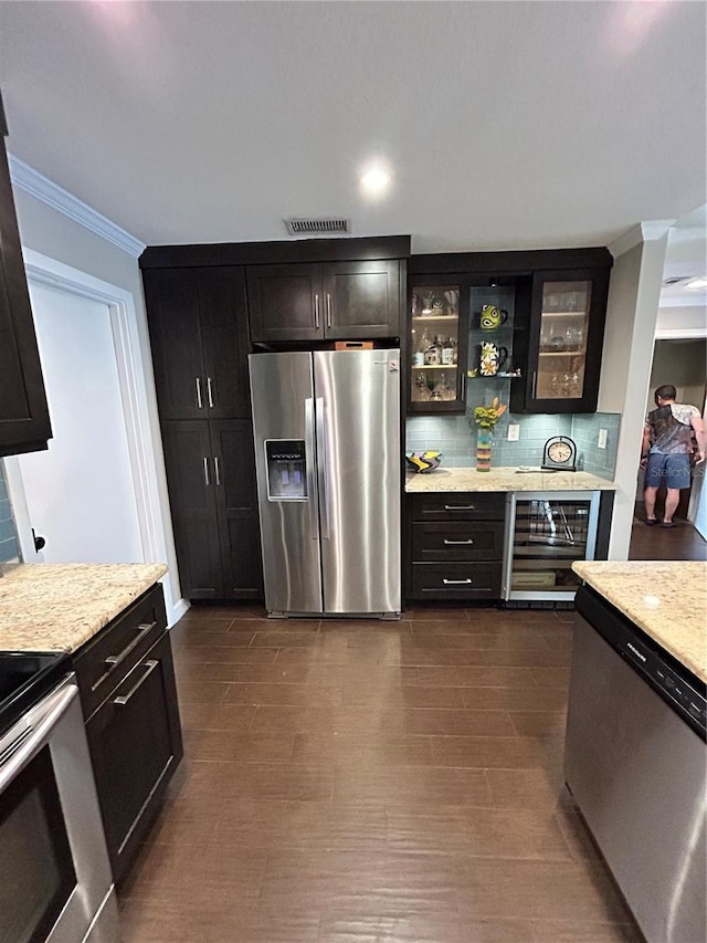 kitchen with visible vents, stainless steel appliances, glass insert cabinets, crown molding, and backsplash