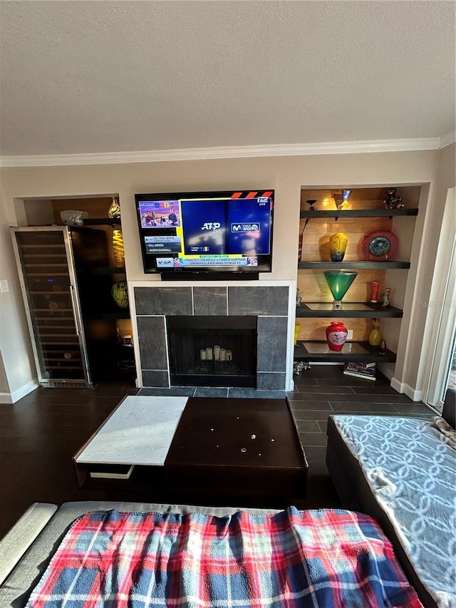 living area featuring built in features, wood finished floors, a fireplace, ornamental molding, and a textured ceiling