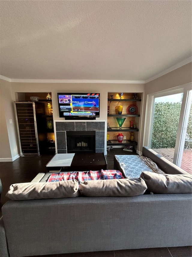 living area with wood finished floors, baseboards, a fireplace, ornamental molding, and a textured ceiling