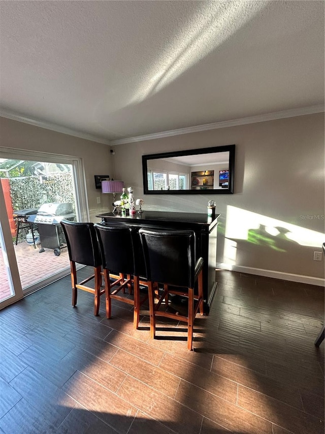 dining space with wood tiled floor, a textured ceiling, baseboards, and ornamental molding