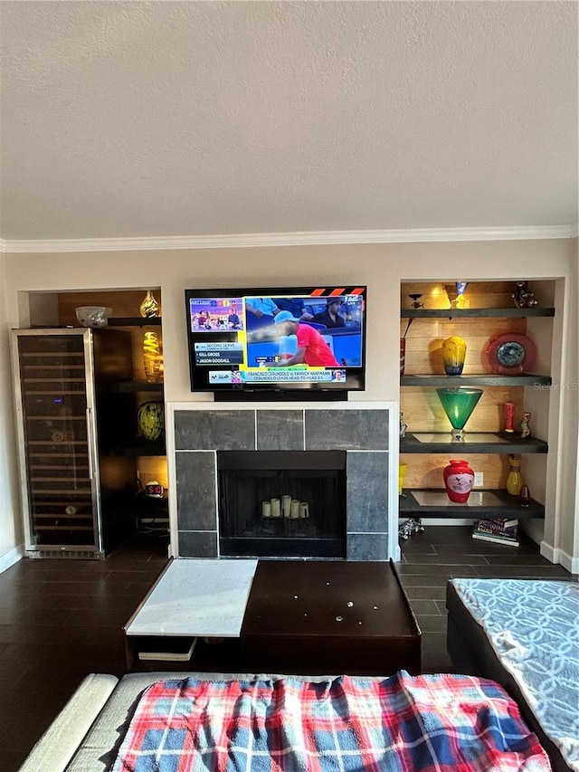 living area with wood finished floors, a fireplace, a textured ceiling, and ornamental molding