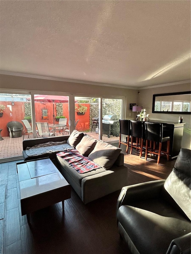 living area with a textured ceiling, hardwood / wood-style floors, and crown molding