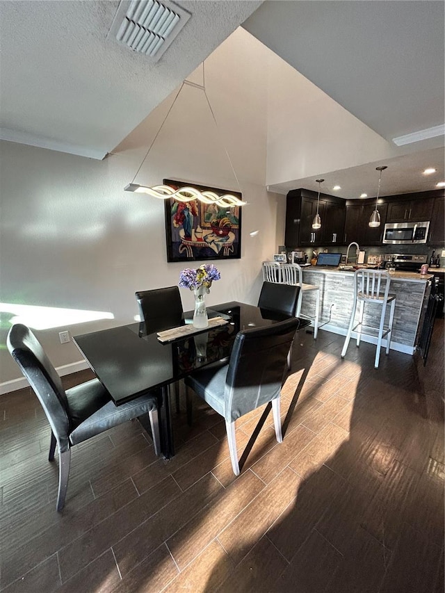 dining room featuring visible vents, baseboards, a textured ceiling, and wood tiled floor