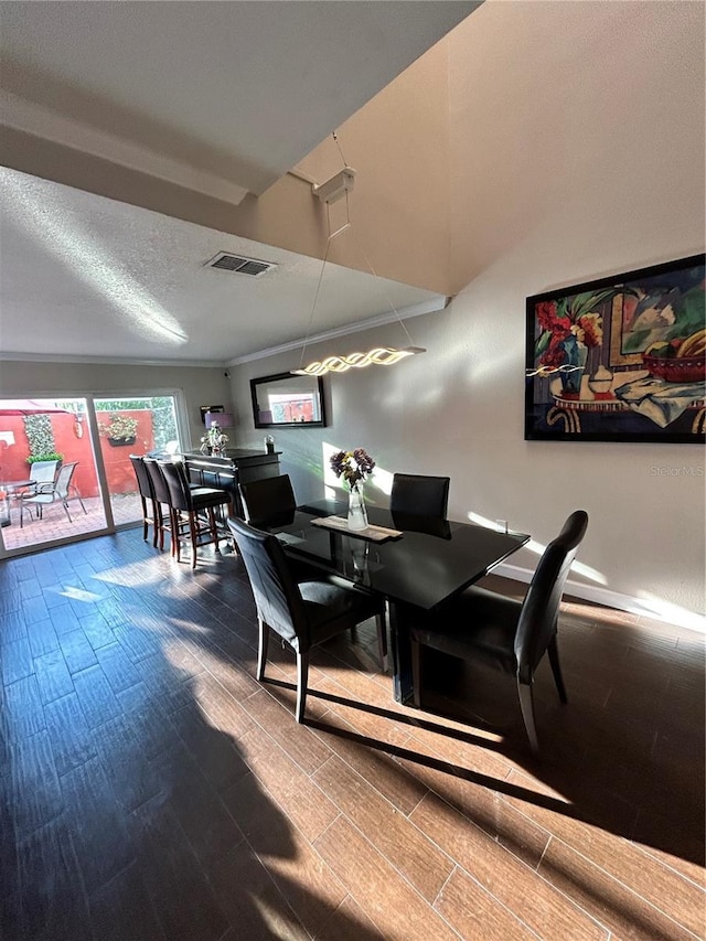 dining room featuring visible vents, a textured ceiling, crown molding, and wood tiled floor