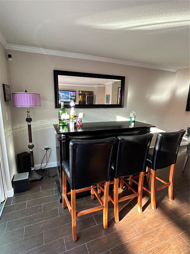 bar featuring wood finish floors, baseboards, a dry bar, and ornamental molding