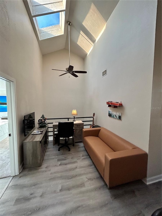 office area with visible vents, high vaulted ceiling, a ceiling fan, a skylight, and light wood finished floors