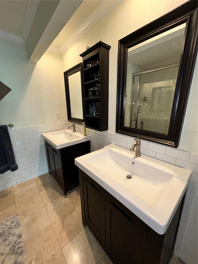 bathroom with two vanities, ornamental molding, a sink, a shower stall, and tile walls