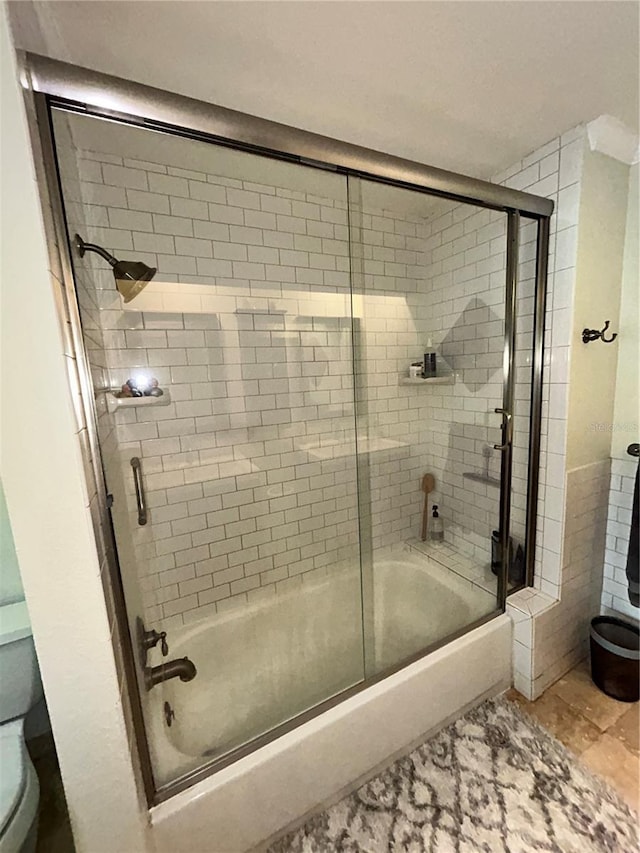 full bathroom with combined bath / shower with glass door and toilet