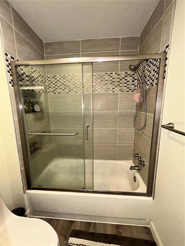 bathroom featuring shower / bath combination with glass door, wood finished floors, and toilet