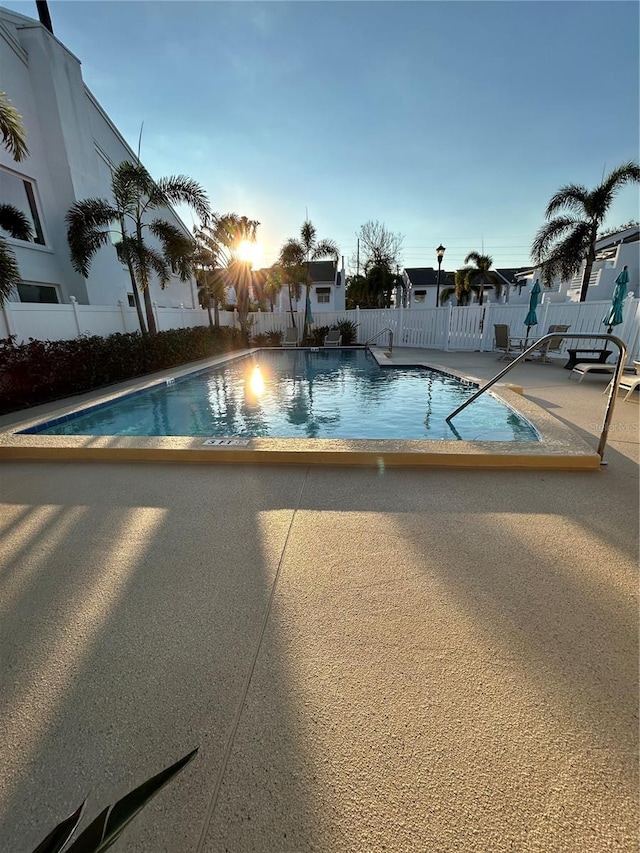 community pool with a patio area and a fenced backyard