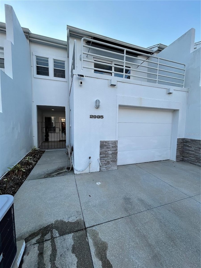 view of front of house with central AC, stucco siding, concrete driveway, and a garage