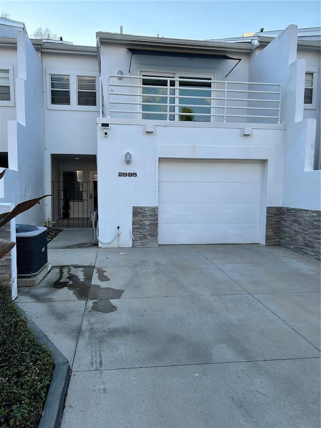 view of front facade with stone siding, stucco siding, driveway, and a balcony