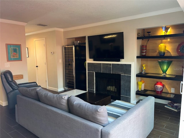 living area featuring baseboards, visible vents, wood finish floors, a fireplace, and ornamental molding