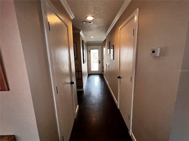 hall featuring baseboards, visible vents, ornamental molding, dark wood-type flooring, and a textured ceiling