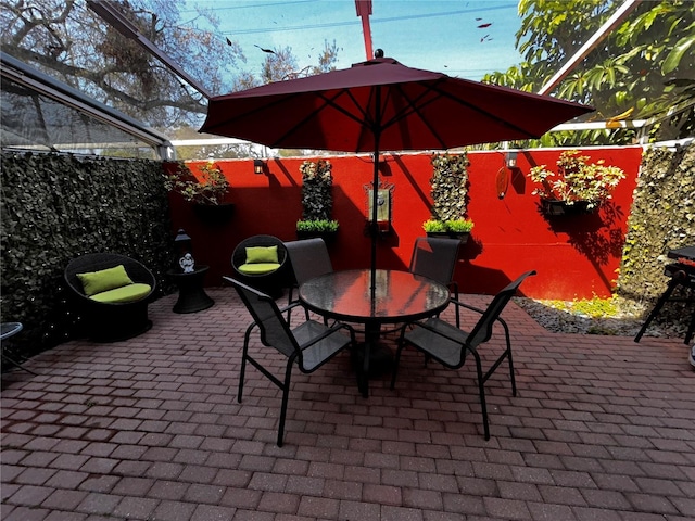 view of patio / terrace featuring glass enclosure and outdoor dining area