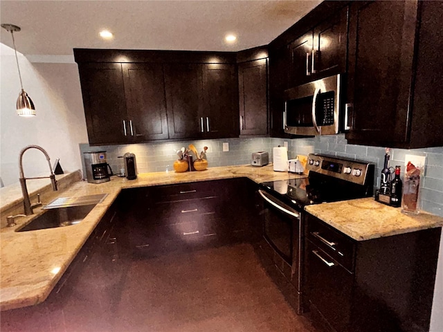 kitchen featuring light stone countertops, a peninsula, a sink, appliances with stainless steel finishes, and tasteful backsplash