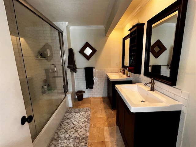 full bath featuring a sink, tile walls, two vanities, and ornamental molding