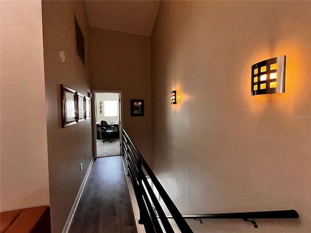 corridor featuring dark wood-style floors, an upstairs landing, and baseboards