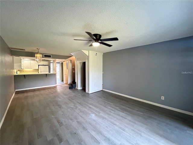 unfurnished living room with dark wood finished floors, visible vents, a ceiling fan, a textured ceiling, and baseboards