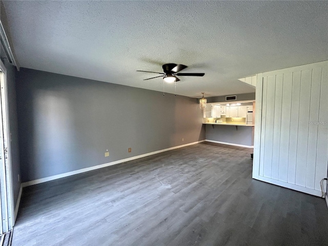 unfurnished living room with dark wood-style floors, a textured ceiling, baseboards, and a ceiling fan