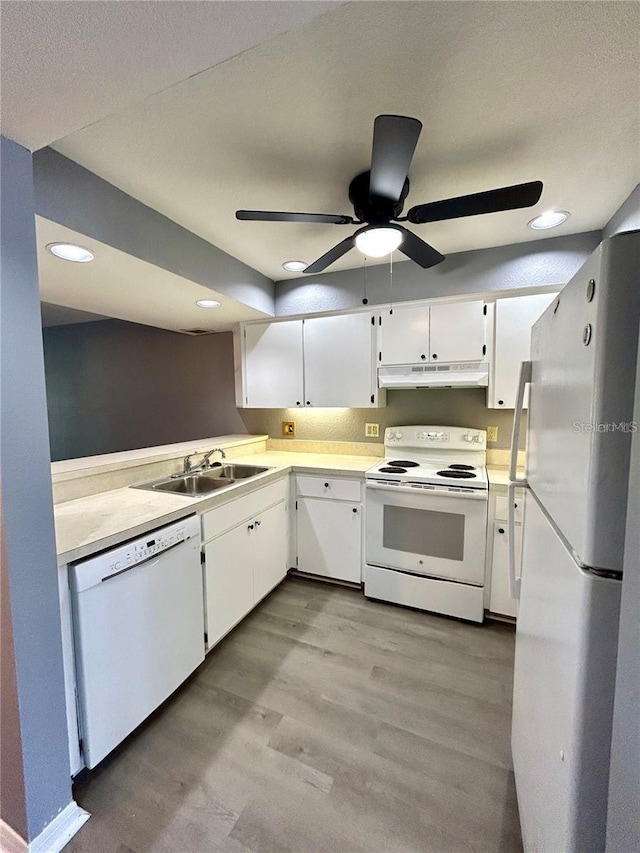 kitchen featuring under cabinet range hood, white appliances, a sink, light wood-style floors, and light countertops