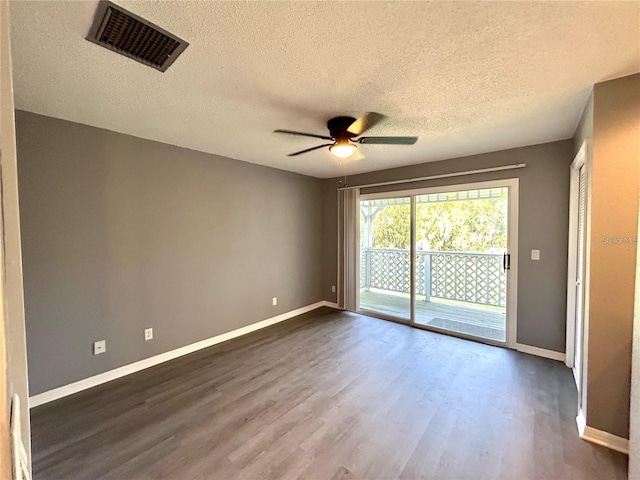 empty room with baseboards, visible vents, and dark wood finished floors