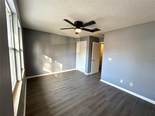 unfurnished room featuring a ceiling fan, a textured ceiling, baseboards, and dark wood-type flooring