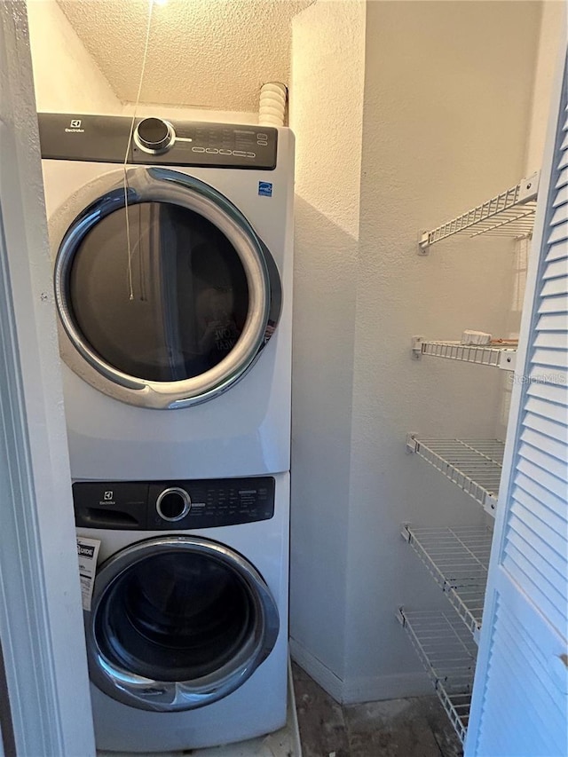 clothes washing area with laundry area, baseboards, and stacked washer and clothes dryer