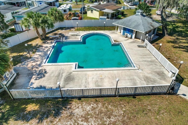 pool with a storage structure, a patio area, a fenced backyard, and an outbuilding