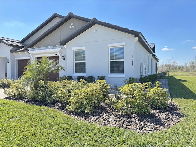 view of side of property with a yard, an attached garage, and stucco siding