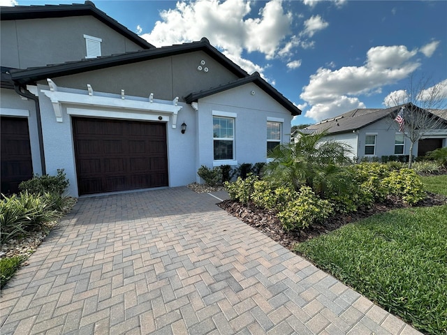 view of front facade with an attached garage, decorative driveway, and stucco siding