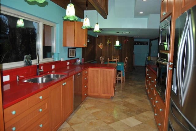 kitchen with dark countertops, a peninsula, hanging light fixtures, stainless steel appliances, and a sink