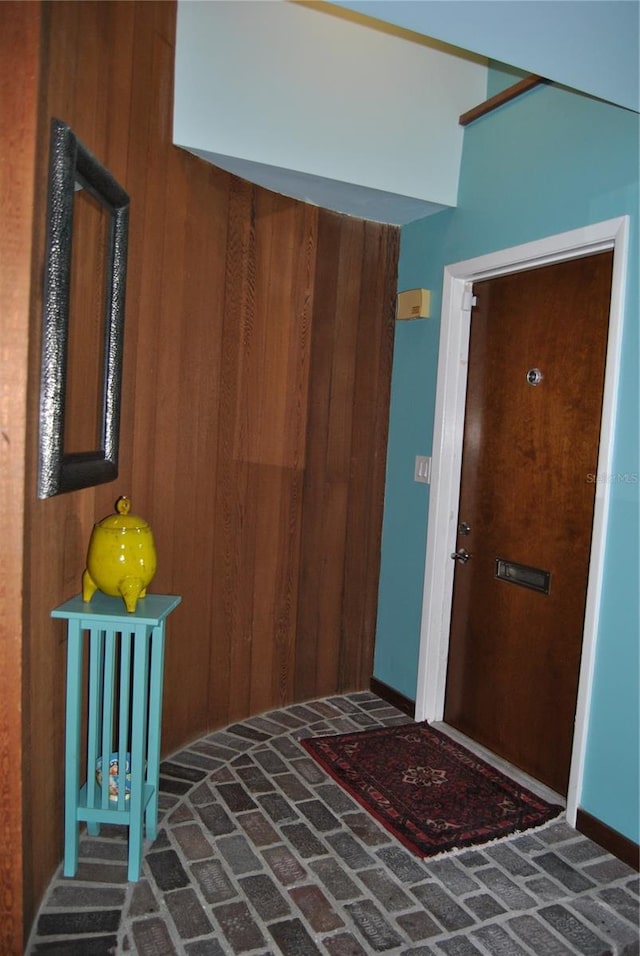 entrance foyer featuring brick floor and wooden walls