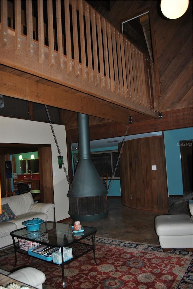 living room with a wood stove, concrete floors, wooden walls, and a high ceiling