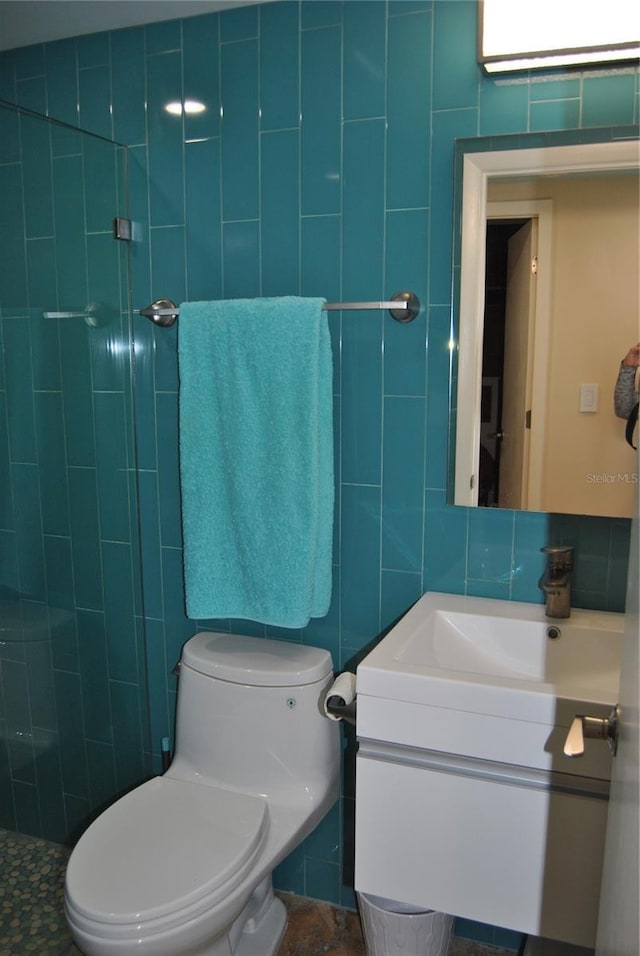 bathroom with toilet, vanity, and tile walls