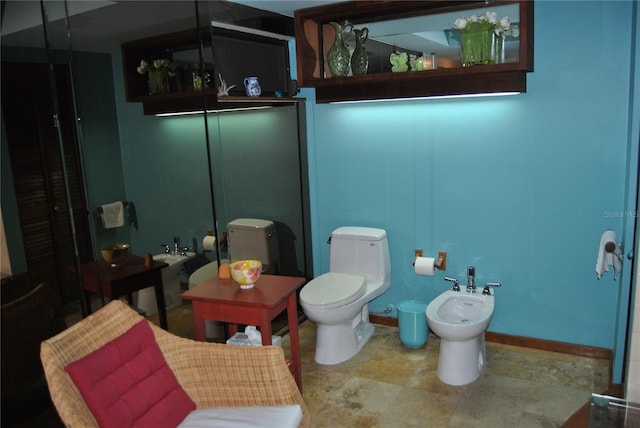 bathroom with baseboards, a bidet, and toilet