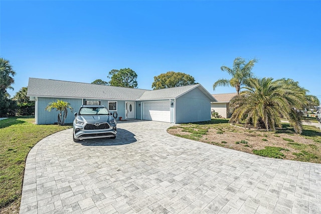 ranch-style house with decorative driveway, an attached garage, and a front yard