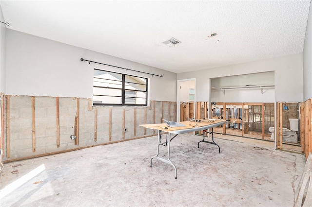 office space featuring a wainscoted wall, a textured ceiling, and visible vents