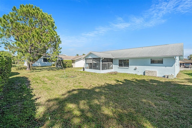 back of property featuring a lawn, a sunroom, and stucco siding