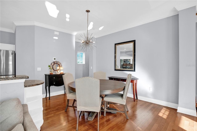 dining room with ornamental molding, an inviting chandelier, baseboards, and wood finished floors